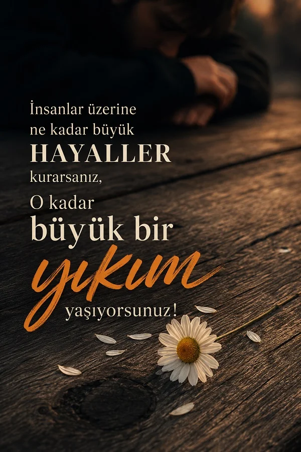 Ahşap masa üzerinde papatya ve arka planda üzgün kişiyle, büyük hayallerin büyük yıkımlar getirdiğini anlatan söz.
